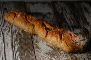 Freshly baked rustic bread loaf resting on an aged wooden table illuminated photo