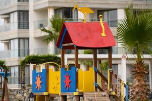 Brightly colored playground structure under a cloudy sky near a coastal setting with vibrant palms in full view photo