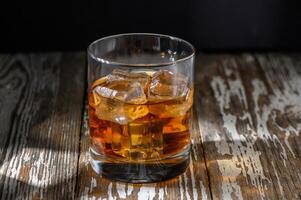 Enjoying a refreshing glass of whiskey on a rustic wooden table in the evening photo