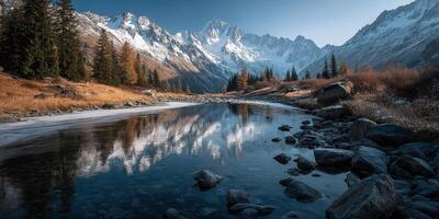 Mountain landscape reflects in calm river during autumn with snow-capped peaks in the background photo