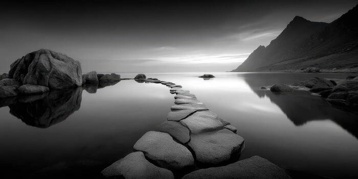 Serene pathway of stones leads to tranquil waters surrounded by mountains at dusk photo