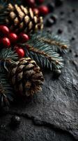 Decorative pinecone and red berries arranged with evergreen needles on dark textured surface during winter festivities photo