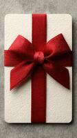 Gift box wrapped in elegant red ribbon on a textured gray surface for a special occasion celebration photo