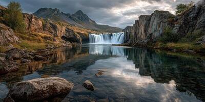 Majestic waterfall cascading into tranquil lake surrounded by rugged mountains in remote natural setting photo