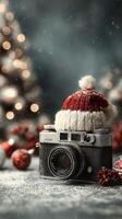 Vintage camera adorned with a festive red and white hat surrounded by holiday decorations in a cozy setting photo