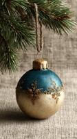 Elegant blue and gold ornament hanging from pine tree branch during winter holiday season photo