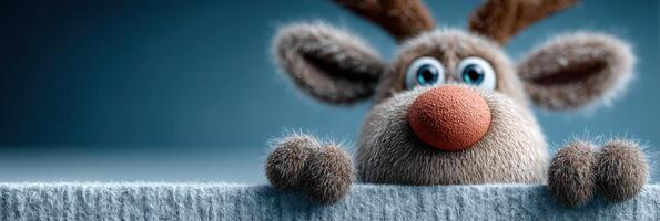 Cute reindeer character peeking over a soft surface with a playful expression in a studio setting photo