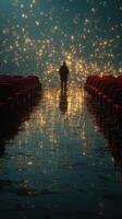 Man stands alone in an illuminated theater with sparkling lights reflecting on the floor photo