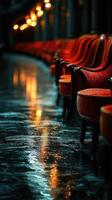 Elegant red chairs line a wet floor as warm lights create a cozy atmosphere in a quiet hallway photo