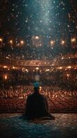 Graduation ceremony at an ornate theater with a graduate facing the audience during a moment of reflection photo