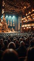 Audience gathered in a festive theater during a holiday performance with a decorated Christmas tree photo