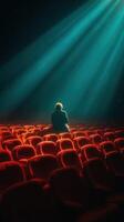 individual sentado solo en un escasamente poblado teatro iluminado por rayos de ligero durante un tranquilo momento de reflexión foto