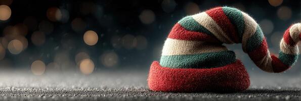 Colorful elf hat resting on a dark surface with soft glowing lights in the background during a festive holiday season photo