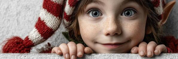 Smiling child dressed as an elf with striped hat in festive setting during winter season photo