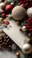 Holiday card surrounded by festive decorations including ornaments, flowers, and pinecones on a textured surface photo