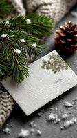 Holiday greeting card with pine branch, cozy knit texture, and pine cone on winter surface photo