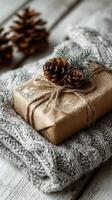 Wrapped gift featuring pine cones and decorative foliage resting on a knitted blanket near pine cones in a cozy setting photo