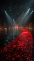 Stunning red pathway illuminated by lights leading into a mysterious reflective water surface at night photo