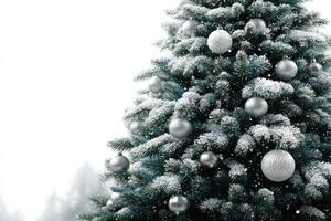 Snowy Christmas tree adorned with silver ornaments in a winter wonderland landscape photo