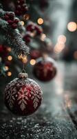 Decorative red Christmas ornament hanging on a snowy tree branch during a winter evening photo
