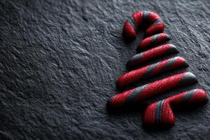 Decorative candy cane tree in red and black colors on textured dark surface creating a festive holiday atmosphere photo