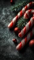 Holiday decorations featuring festive candy canes and ornaments on a dark surface with evergreen accents photo