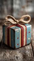 Small wrapped present with red ribbon and burlap bow on rustic wooden surface shines with festive charm during holiday season photo