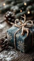Christmas gift wrapped in blue fabric with snowflake pattern, adorned with a wooden reindeer, pine cones scattered on a rustic table photo