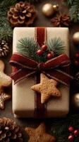 Holiday gift wrapped in sparkly gold paper with red ribbon, pine branches, and gingerbread cookie on a festive table photo