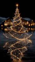 Sparkling Christmas tree adorned with lights reflecting on a calm lake during winter evenings photo