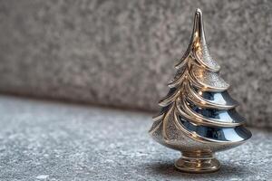 Silver Christmas tree decoration placed on a gray stone surface creating a festive ambiance for the holiday season photo