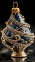 Intricate glass ornament with golden swirls and sparkling details displayed on a dark surface during the holiday season photo