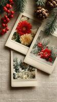 Festive collection of winter floral polaroids with red flowers and pine accents arranged on a textured fabric background photo