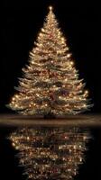 Warmly lit Christmas tree glowing in darkness with mirrored reflection on smooth surface during holiday season photo