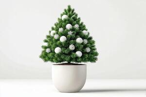 Green artificial Christmas tree decorated with white ornaments displayed on a plain background in a cozy indoor setting photo