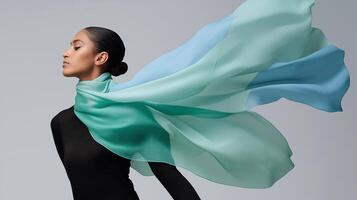 Elegant woman in black with a flowing ocean-colored scarf, evoking calm, movement, and marine inspiration in a minimalist fashion setting. Perfect for style and textile concepts. photo