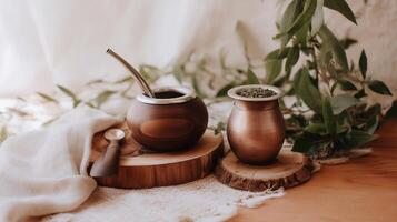 Traditional yerba mate tea scene with calabash gourds, bombilla, and dried mate leaves. Warm rustic setup with wood, fabric, and natural greenery in soft daylight. photo