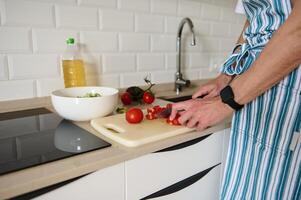 Man Wearing Apron Preparing a Fresh Salad in a Modern Kitchen photo