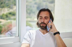 Bearded Man Engaged in a Phone Call at a Bright Minimalist Home Office photo