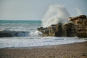 Majestic Ocean Waves Crashing Against Coastal Rock Formation with Splashes photo