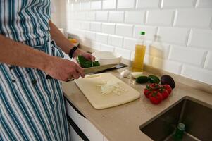 Man in Apron Preparing Fresh Veggies in a Modern Home Kitchen photo