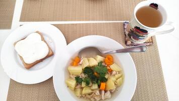 Chicken soup with potatoes, carrots and coriander, bread and herbal tea for healthy lunch dinner photo