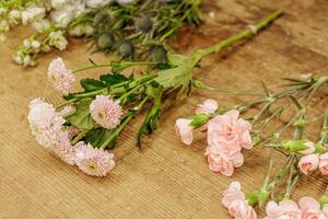 Florist arranging pink carnations and chrysanthemums on wooden table, mothers day photo