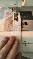 Close-up of skilled hands guiding delicate sheer fabric through sewing machine, showcasing intricate stitching process and creative textile artistry in action photo