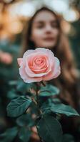 A woman is standing in front of a pink rose photo