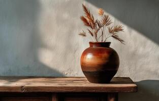 A vase with dried flowers sitting on a wooden table photo