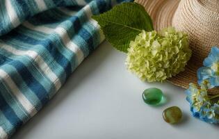 A hat, green stones and flowers on a blue and white striped cloth photo