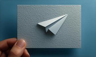 A person holding a paper airplane on a square card photo