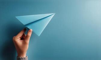 A person holding a paper airplane over a blue background photo