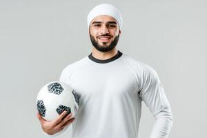 Smiling Muslim Soccer Player Holding a Ball Against a Grey Background photo